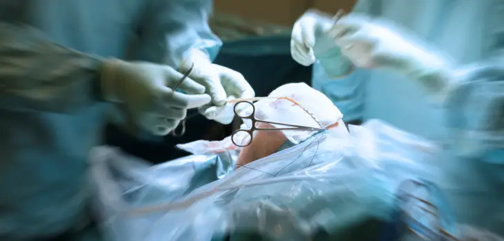 A doctor and a nurse performing knee surgery.,